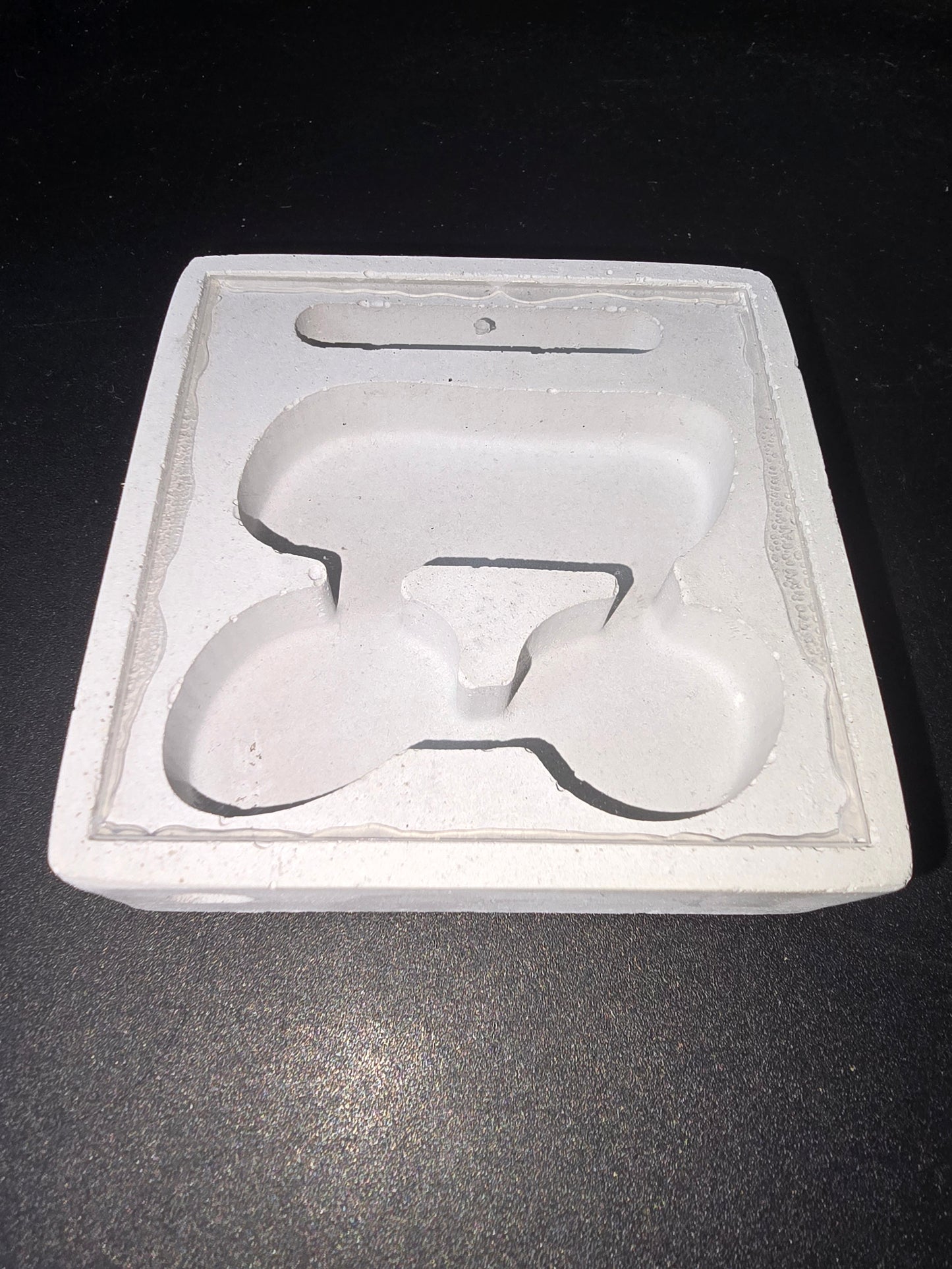 Plaque en coton ou fibre avec empreinte en forme de logo PETIT, relief sculpté blanc sur fond clair, cadre rectangulaire.