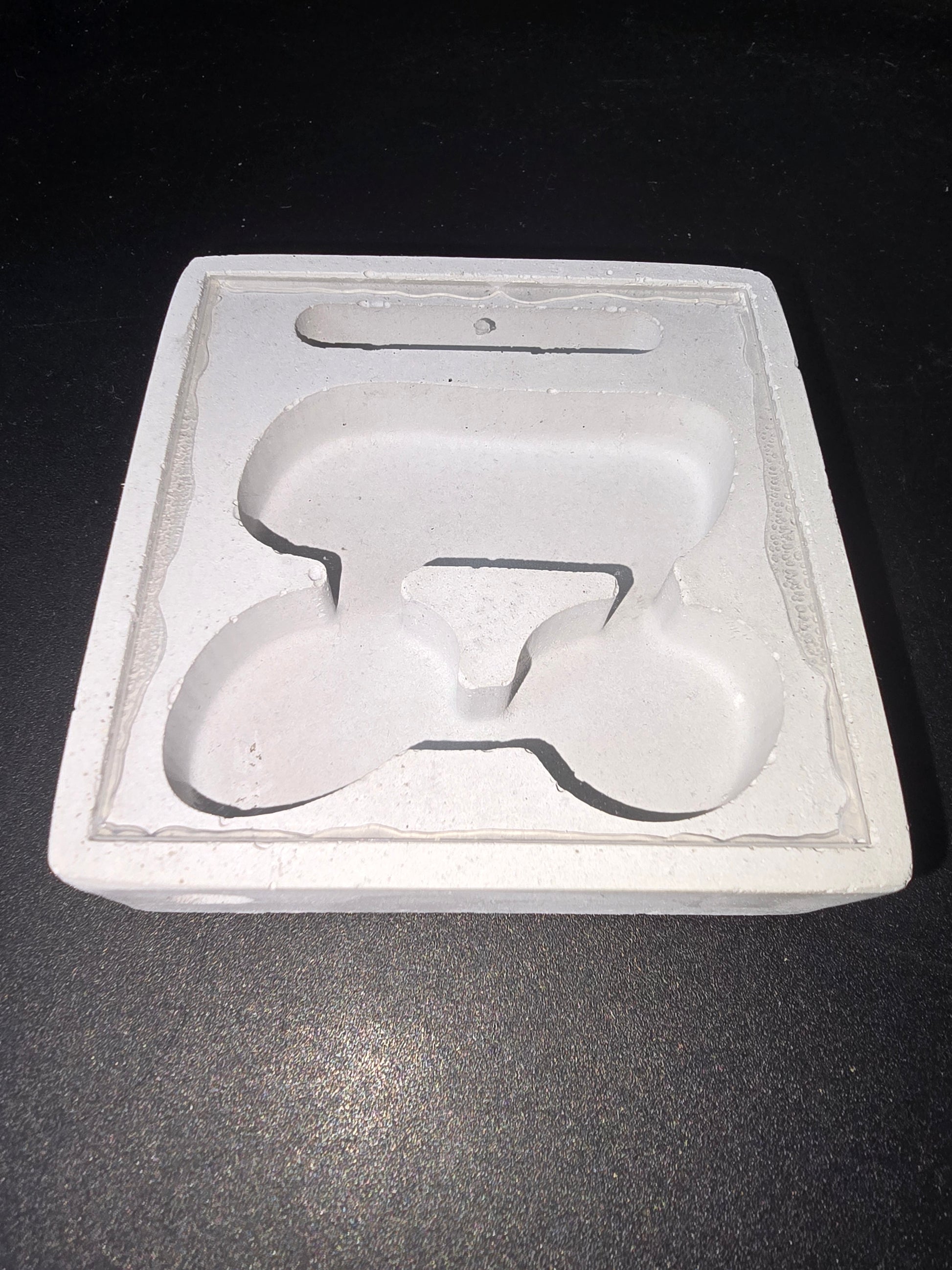 Plaque en coton ou fibre avec empreinte en forme de logo PETIT, relief sculpté blanc sur fond clair, cadre rectangulaire.